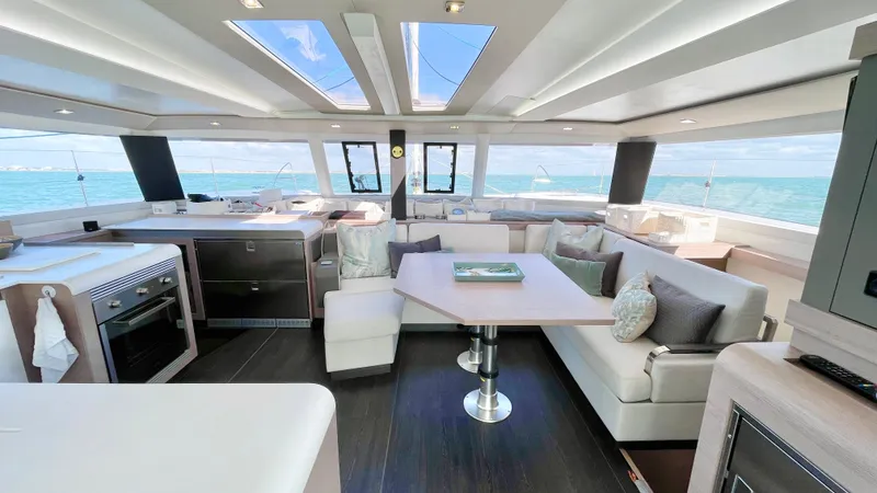 Moon Doggie Yacht Photos Pics Luxurious interior of 2022 Fountaine Pajot Tanna 47 catamaran with modern kitchen and seating area.