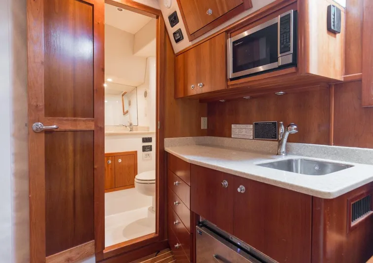 Tin Bender Yacht Photos Pics 2009 Albemarle 360 XF yacht interior with kitchenette and bathroom, featuring wood cabinetry and modern amenities.