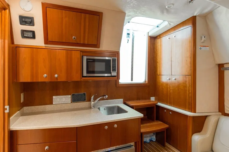 Tin Bender Yacht Photos Pics 2009 Albemarle 360 XF yacht interior with kitchenette, featuring wood cabinets and a microwave.