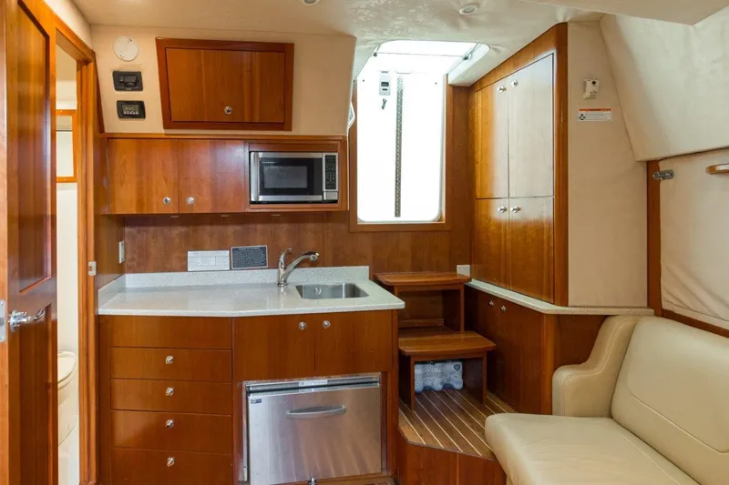 Tin Bender Yacht Photos Pics 2009 Albemarle 360 XF yacht interior with kitchenette, wooden cabinets, and seating area.