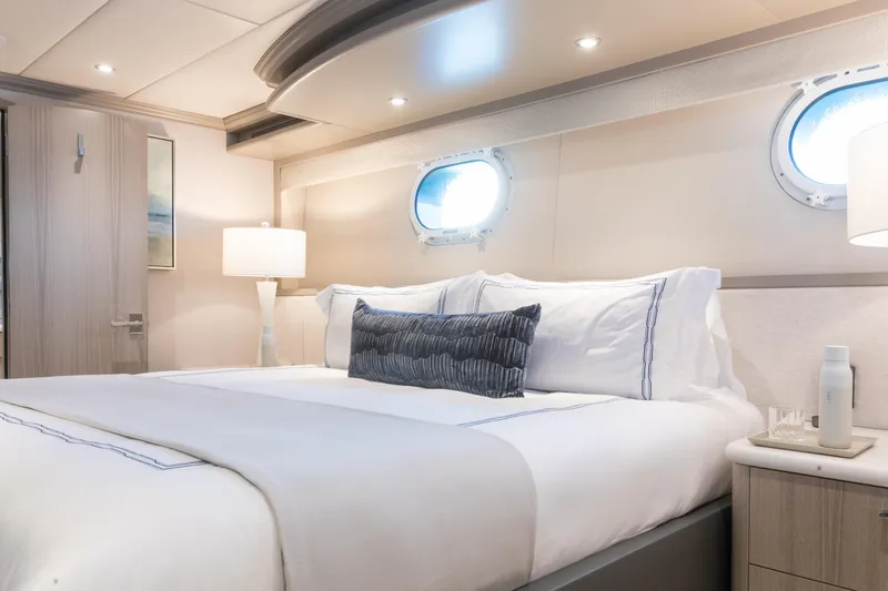No Bad Ideas Yacht Photos Pics Luxurious bedroom interior on 2000 Trinity Yachts Trinity 160, featuring elegant bedding and porthole windows.