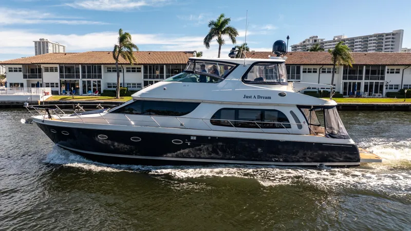 Just A Dream Yacht Photos Pics 2005 Carver 56 Voyager yacht cruising near waterfront buildings and palm trees.