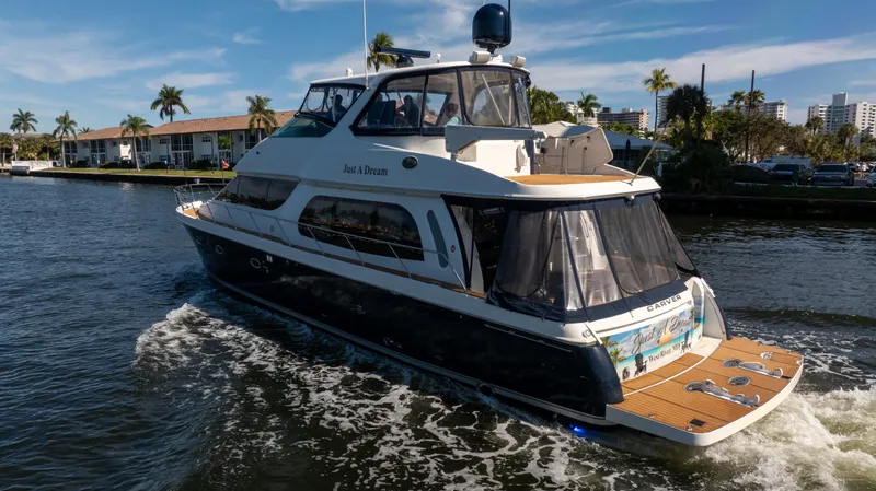 Just A Dream Yacht Photos Pics 2005 Carver 56 Voyager yacht cruising on a sunny waterway with palm trees in the background.