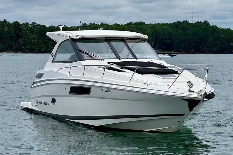  Yacht Photos Pics 2018 Regal 35 Sport Coupe cruising on a serene lake with forested shoreline.