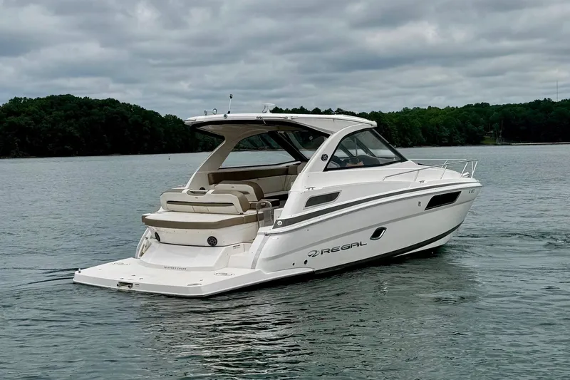  Yacht Photos Pics 2018 Regal 35 Sport Coupe boat on a calm lake under cloudy skies.