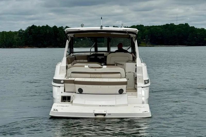  Yacht Photos Pics 2018 Regal 35 Sport Coupe boat on a lake, rear view with lush forest backdrop.
