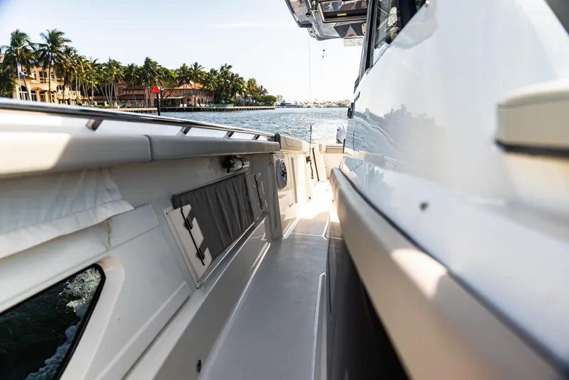  Yacht Photos Pics 2021 Pursuit 428 boat side view on a sunny day near palm-lined waterfront.