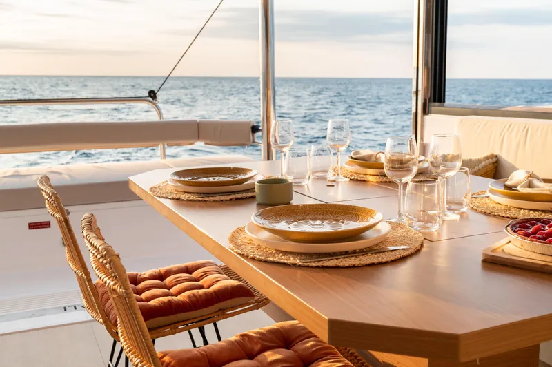Roxy Yacht Photos Pics Elegant dining setup on Bali 4.4 yacht, 2022 model, with ocean view at sunset.