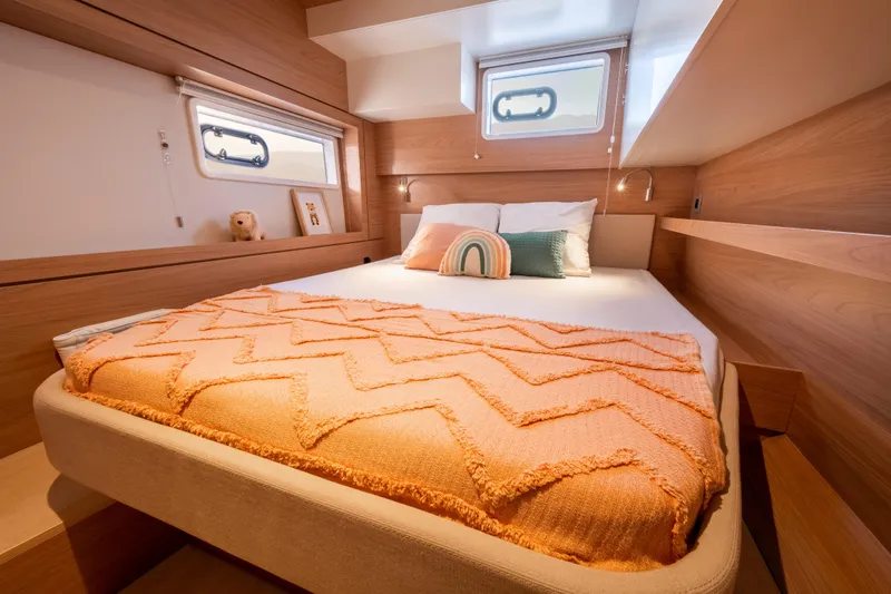 Roxy Yacht Photos Pics Cozy bedroom in 2022 Bali 4.4 yacht with orange blanket and decorative pillows.