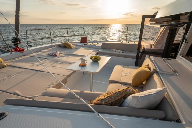 Roxy Yacht Photos Pics Luxurious Bali 4.4 catamaran deck with seating, table, and ocean sunset view, 2022 model.