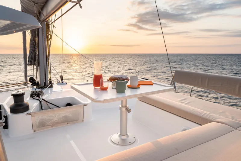 Roxy Yacht Photos Pics Luxury Bali 4.4 yacht deck with sunset view, table setting, and ocean backdrop, 2022 model.