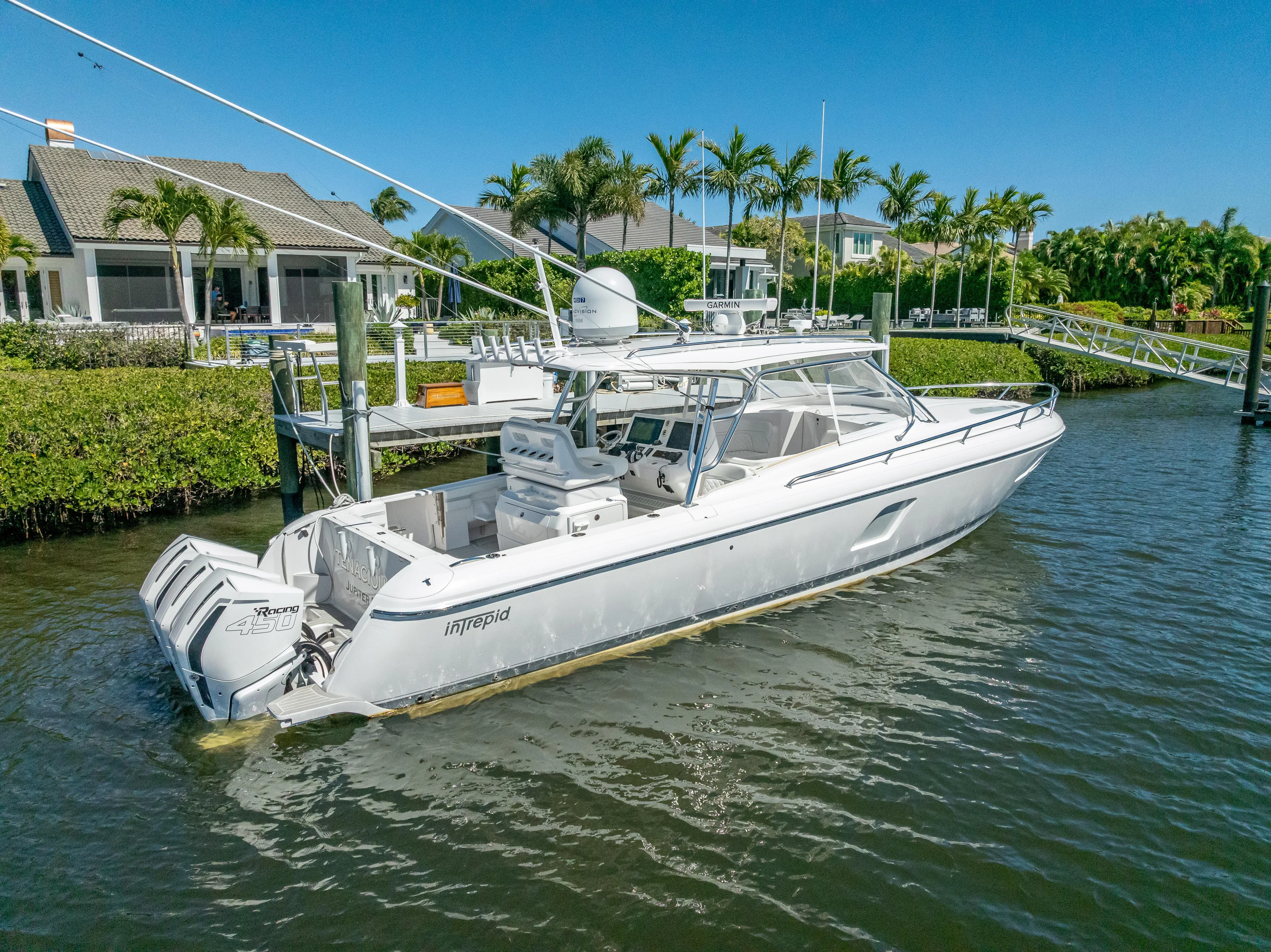  Yacht Photos Pics 2020 Intrepid 407 Cuddy boat docked near waterfront homes, surrounded by lush greenery.