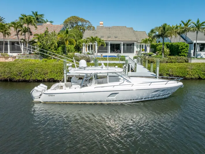  Yacht Photos Pics 2020 Intrepid 407 Cuddy boat docked by waterfront homes, surrounded by lush greenery.