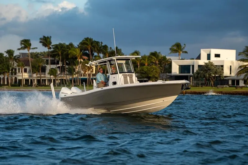  Yacht Photos Pics 2025 Caymas 291 HB boat cruising on water near modern waterfront homes.