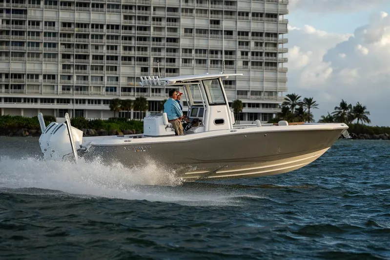  Yacht Photos Pics 2025 Caymas 291 HB boat cruising on water near a modern building.