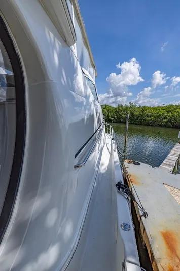 Paradise Yacht Photos Pics 2002 Carver 466 Motor Yacht docked by a serene waterway under a clear blue sky.