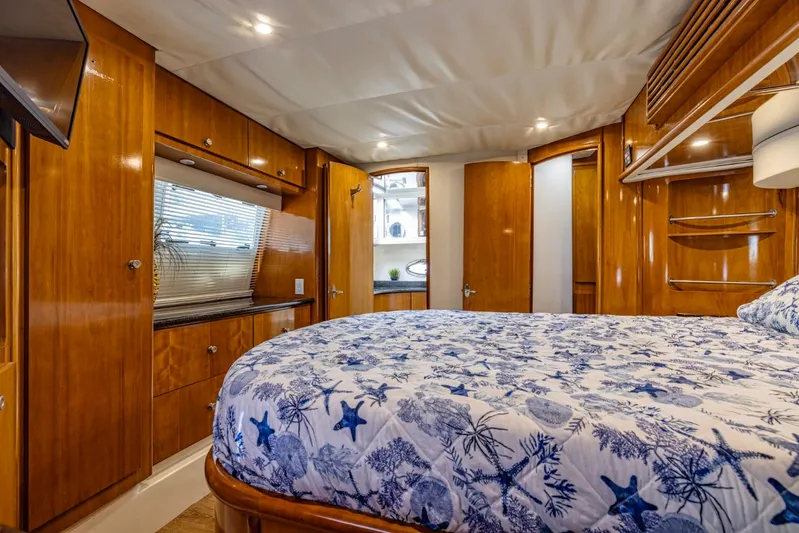 Paradise Yacht Photos Pics Luxurious 2002 Carver 466 Motor Yacht bedroom with wood cabinetry and nautical-themed bedding.