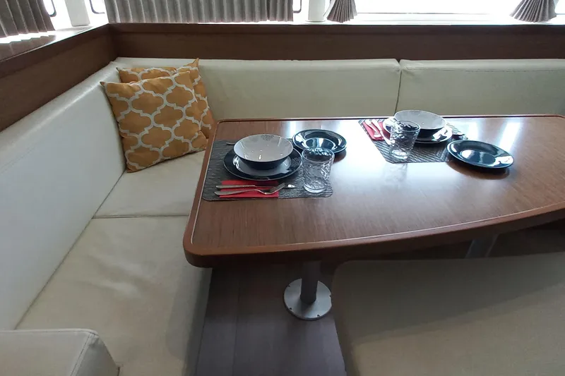 Always Sunday Yacht Photos Pics Interior dining area of 2020 Lagoon 42 catamaran with set table and cushions.