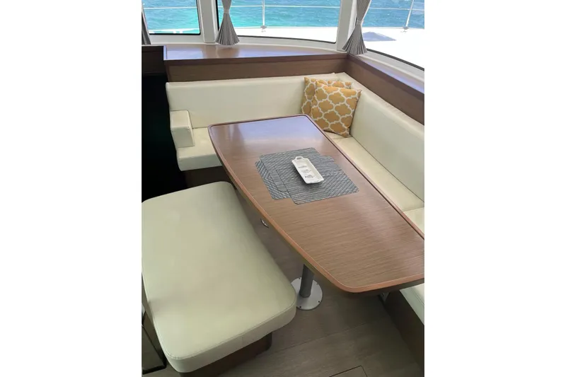 Always Sunday Yacht Photos Pics Interior of 2020 Lagoon 42 catamaran with dining area, wooden table, and cushioned seating.