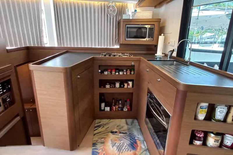 Always Sunday Yacht Photos Pics Modern kitchen interior of 2020 Lagoon 42 yacht with wooden cabinetry and appliances.