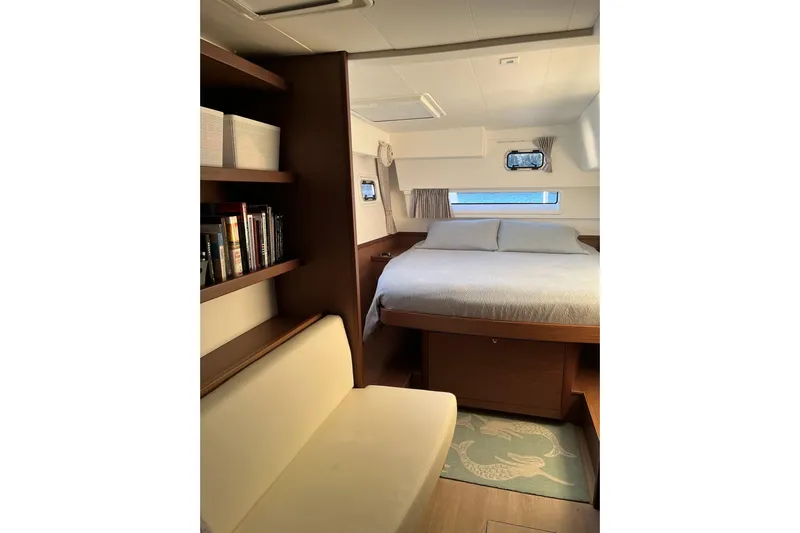 Always Sunday Yacht Photos Pics Interior of 2020 Lagoon 42 yacht cabin with bed, bookshelf, and seating area.