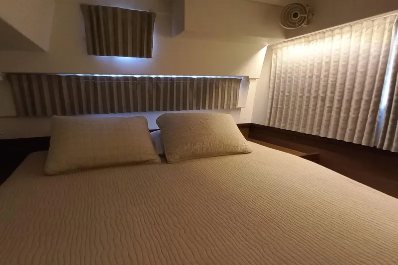 Always Sunday Yacht Photos Pics Cozy bedroom interior of 2020 Lagoon 42 catamaran with soft lighting and striped curtains.