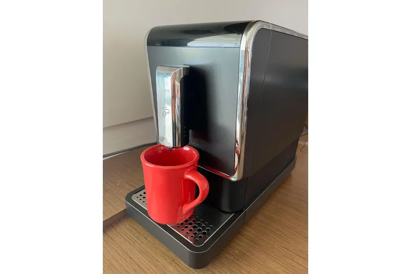 Always Sunday Yacht Photos Pics Modern coffee machine with a red mug on a wooden countertop.