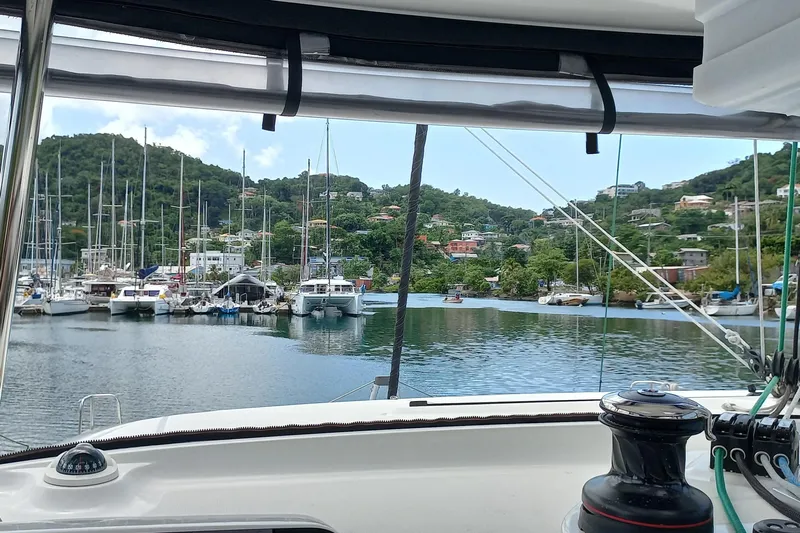 Always Sunday Yacht Photos Pics View from a 2020 Lagoon 42 catamaran, overlooking a marina with sailboats and lush hills.