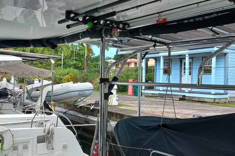 Always Sunday Yacht Photos Pics 2020 Lagoon 42 catamaran docked with dinghy and blue building in background.