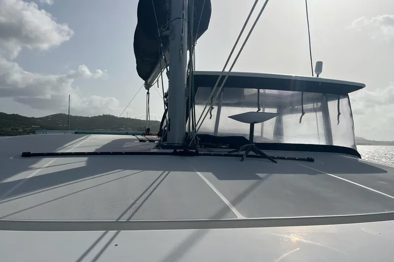Always Sunday Yacht Photos Pics 2020 Lagoon 42 catamaran deck with mast and sail, under a cloudy sky.