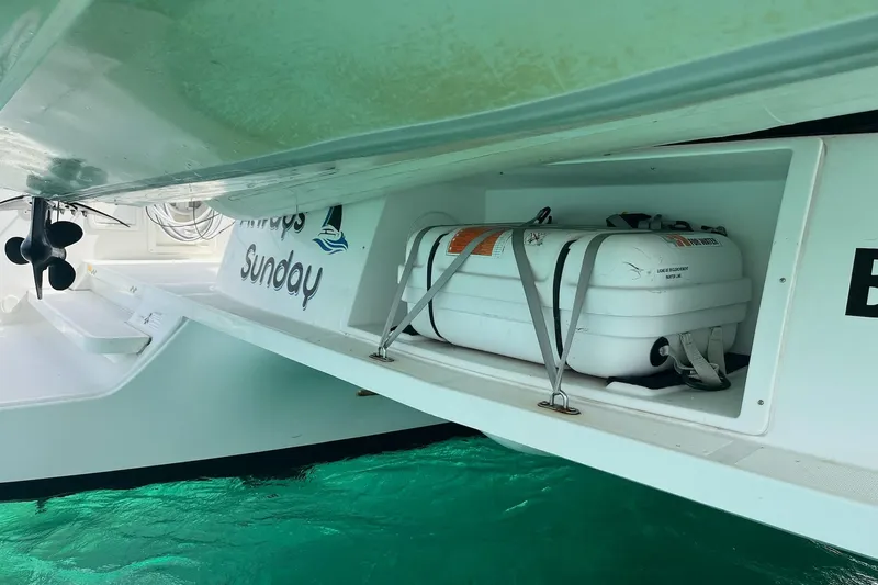 Always Sunday Yacht Photos Pics 2020 Lagoon 42 catamaran with secured life raft, floating on turquoise water.