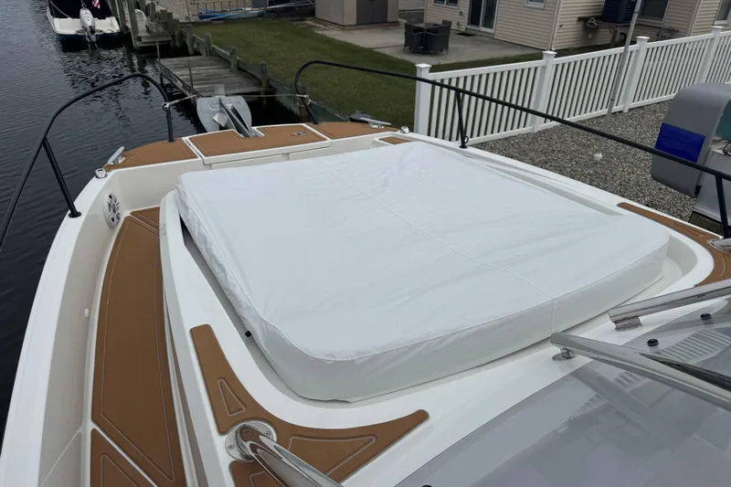  Yacht Photos Pics 2024 Beneteau Flyer 9 SUNdeck with cushioned sunbathing area, docked by a waterfront.