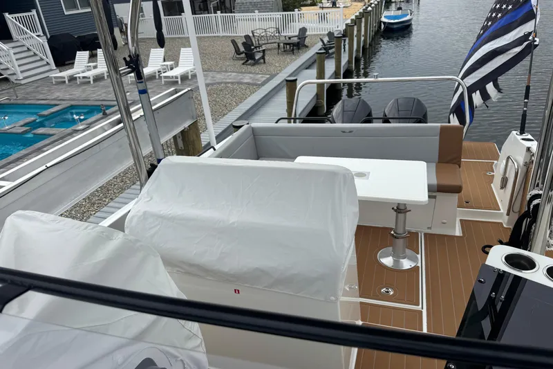  Yacht Photos Pics 2024 Beneteau Flyer 9 SUNdeck boat with seating area, docked near a poolside.