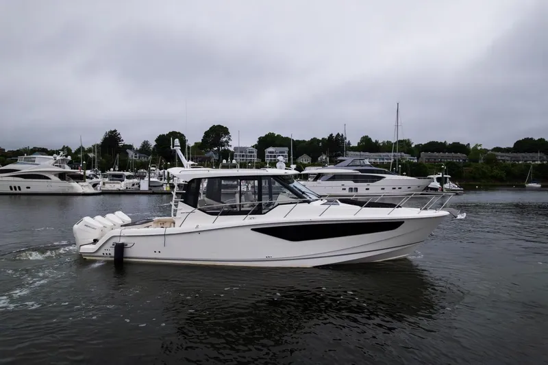  Yacht Photos Pics 2024 Boston Whaler 405 Conquest cruising in a marina with other yachts.