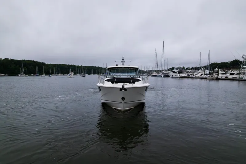  Yacht Photos Pics 2024 Boston Whaler 405 Conquest cruising in a marina, surrounded by sailboats.