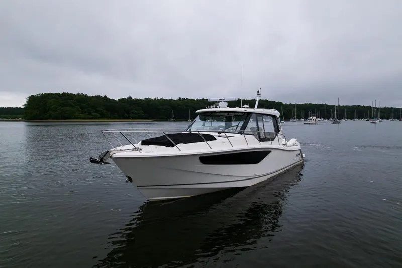  Yacht Photos Pics 2024 Boston Whaler 405 Conquest boat on calm water, overcast sky, forested shoreline.
