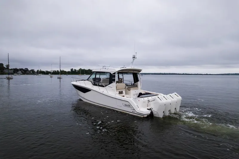  Yacht Photos Pics 2024 Boston Whaler 405 Conquest boat cruising on a calm lake under cloudy skies.