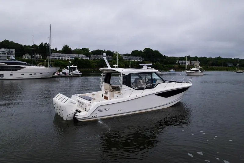  Yacht Photos Pics 2024 Boston Whaler 405 Conquest boat on calm water, surrounded by other vessels.