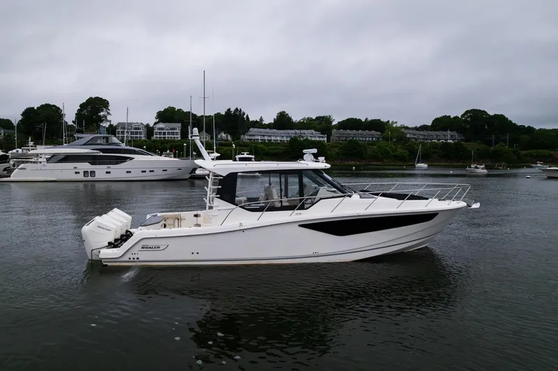  Yacht Photos Pics 2024 Boston Whaler 405 Conquest boat on calm water, surrounded by other vessels.