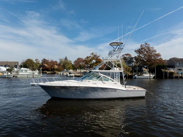 Ryfly Yacht Photos Pics 2004 Cabo 40 Express boat on calm water, surrounded by trees and houses.