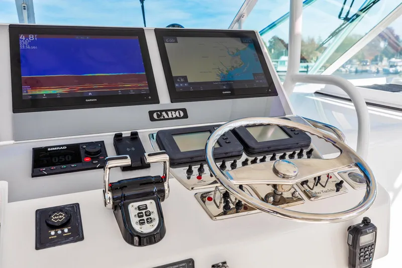 Ryfly Yacht Photos Pics Control panel of 2004 Cabo 40 Express boat with navigation screens and steering wheel.