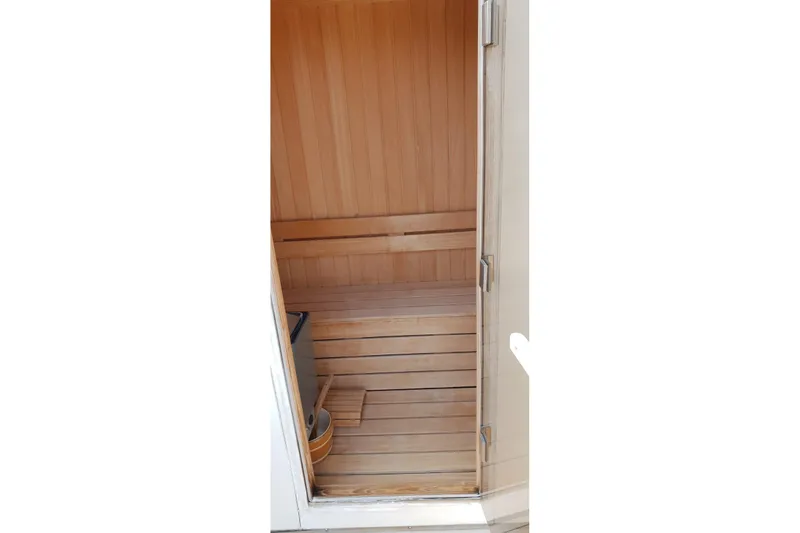  Yacht Photos Pics Wooden sauna interior with bench and bucket, viewed through an open door.