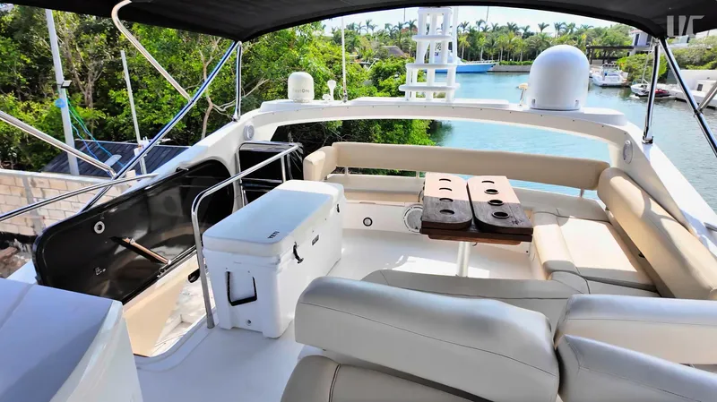 Phantom Yacht Photos Pics Luxurious 2011 Sunseeker Manhattan 63 yacht interior with seating and table, docked by lush greenery.