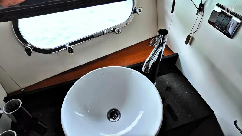 Phantom Yacht Photos Pics Luxurious bathroom sink on 2011 Sunseeker Manhattan 63 yacht, featuring modern fixtures and porthole window.