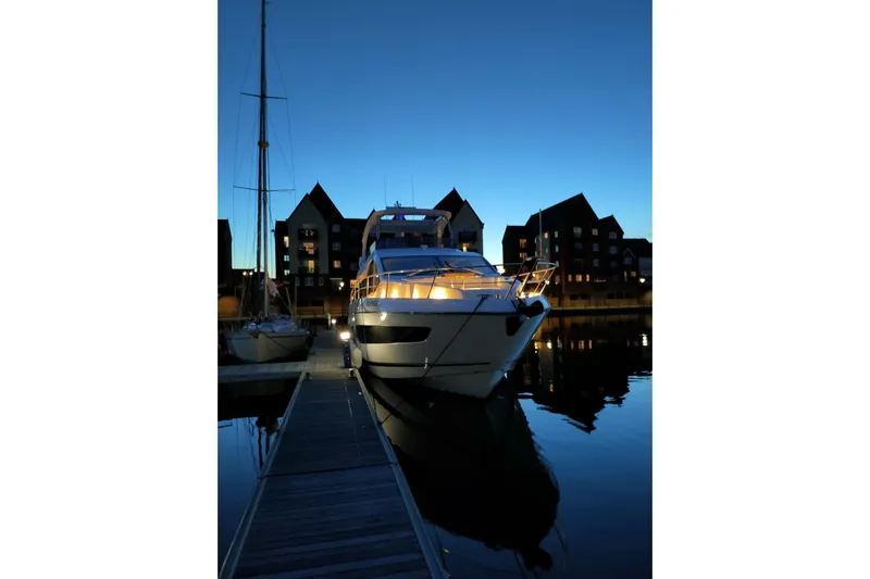 Elixa Yacht Photos Pics Sunseeker Manhattan 68 yacht docked at twilight, 2022 model, illuminated against evening sky.