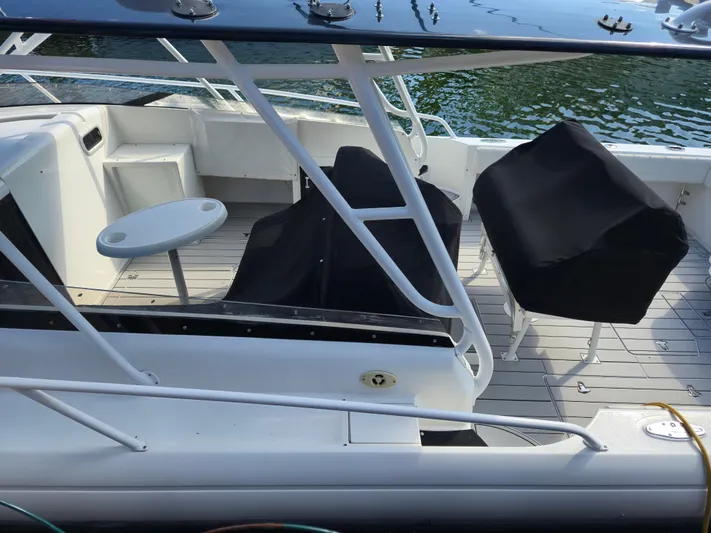  Yacht Photos Pics 2002 Intrepid 377 Walkaround boat deck with covered seating and table, docked by water.