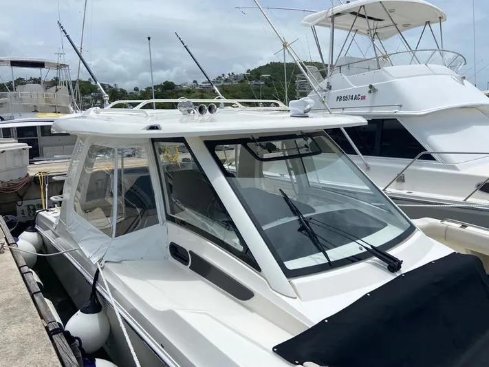  Yacht Photos Pics 2021 Boston Whaler 350 Realm boat docked at marina, featuring sleek design and enclosed cabin.