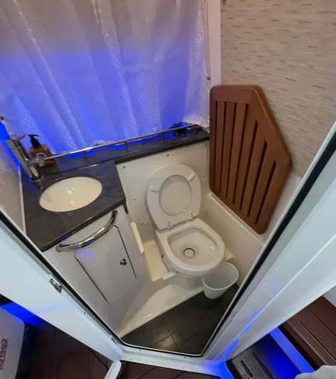  Yacht Photos Pics 2021 Boston Whaler 350 Realm bathroom with toilet, sink, and blue ambient lighting.
