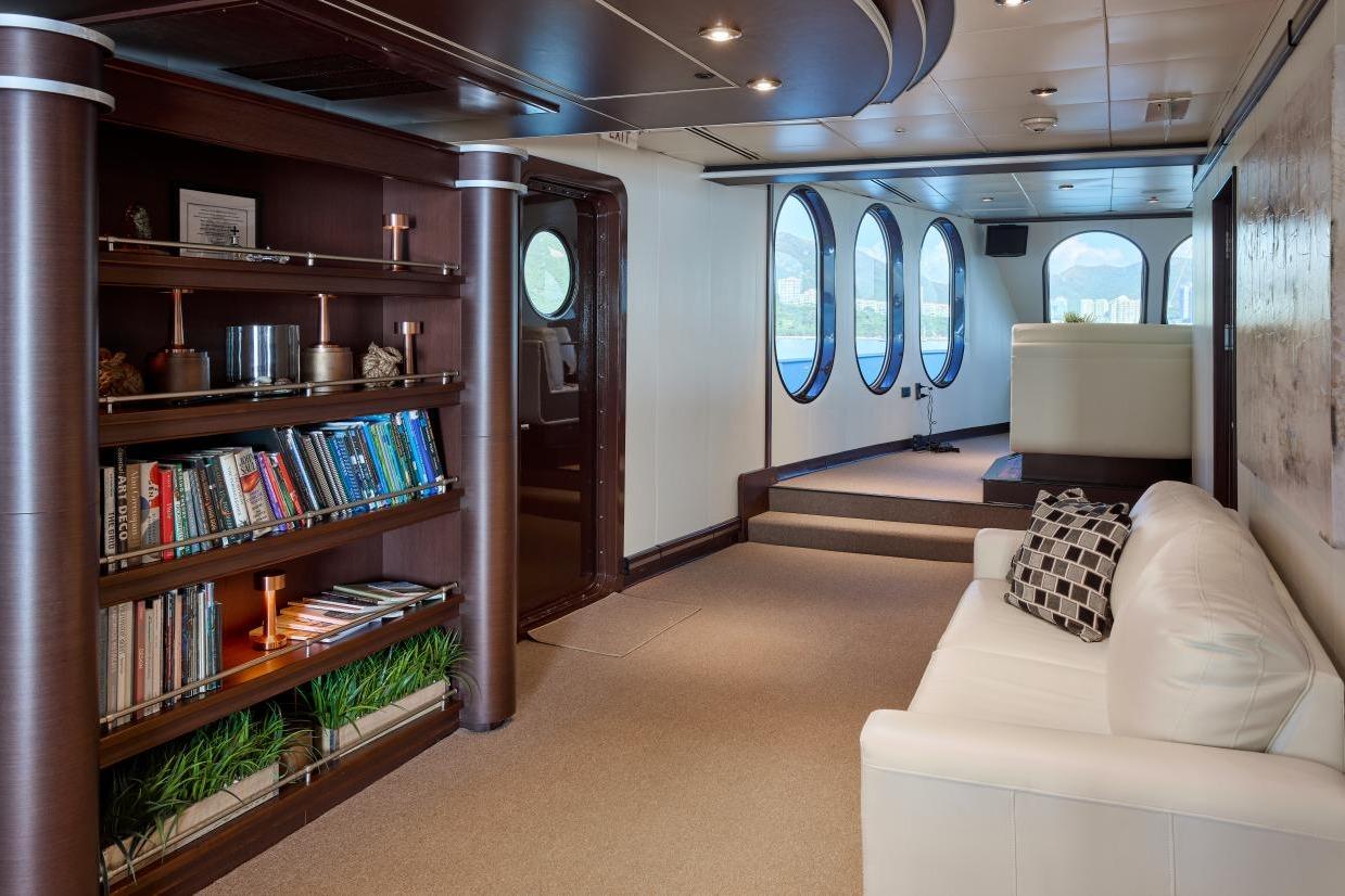 Luxurious interior of 1982 Shadow Marine Custom Expedition Yacht with bookshelves and porthole windows.