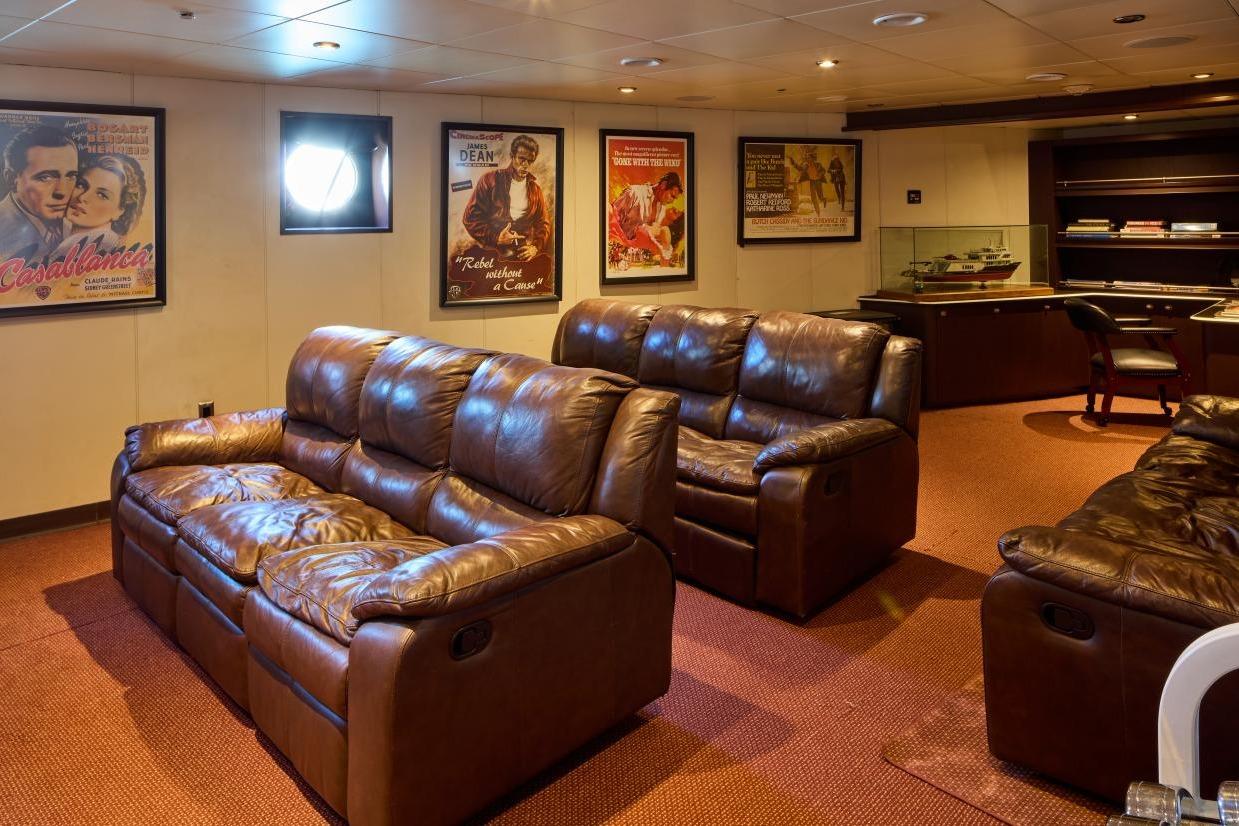 Luxurious yacht interior with leather sofas, vintage movie posters, and a model ship display.